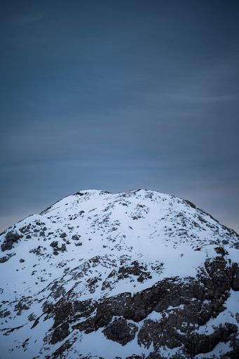 The vertical low angle shot of snowy mountain high in the winter