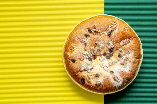 A pie with berries and nuts sprinkled with sweet powder isolated on a yellow and green background