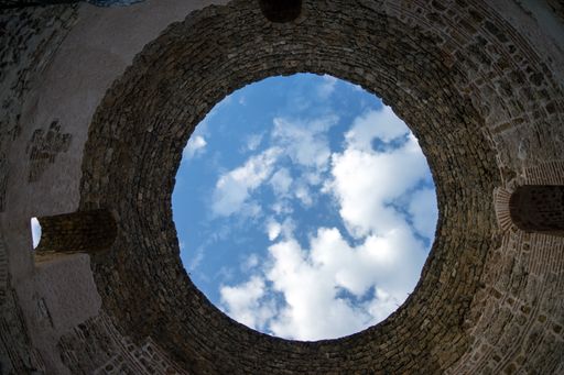 A view of the sky from the inside of a tower with a round-shaped hole.