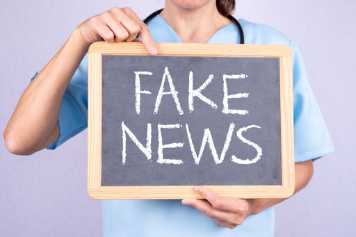 A nurse points to a board that says FAKE NEWS