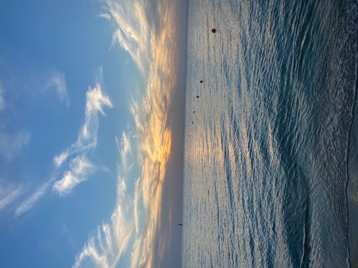 A vertical shot of a calm sea or ocean at sunset with beacons and a boat seen in the distance