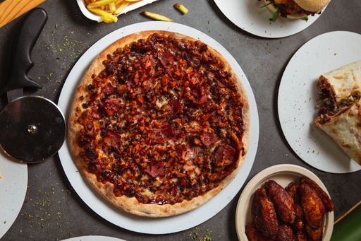 A top view of the table with pizza, chicken wings, and burritos