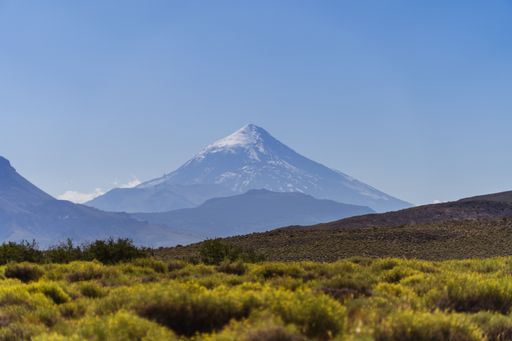 A scenic view of a grassy field and a mountain in the background under a blue sky