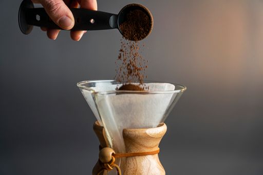 closeup shot of man adding coffee in pour over glass