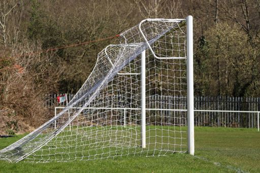 A closeup of a white football game goal on the grass in a field