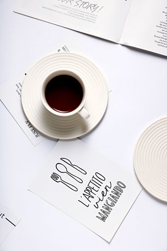 A top view of a cup of coffee on a magazine lying on a white surface