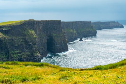 A scenic view of ocean waves crashing against the Cliffs of Moher in Ireland