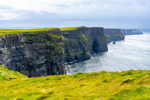 A scenic view of ocean waves crashing against the Cliffs of Moher in Ireland