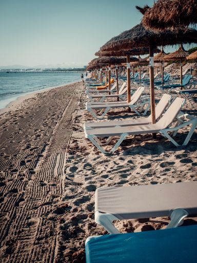 A row of empty lounge chairs on a sandy beach in Mallorca on a sunny day