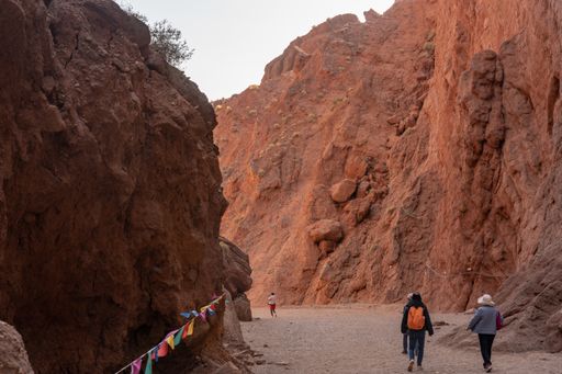 Some tourists hiking in the gorge next to cliffs.