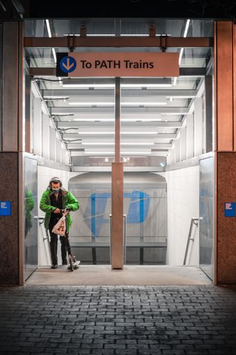 A man leaving a train station with a scooter