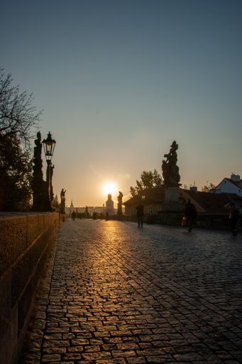 A vertical shot of people walking on bridge during sunset