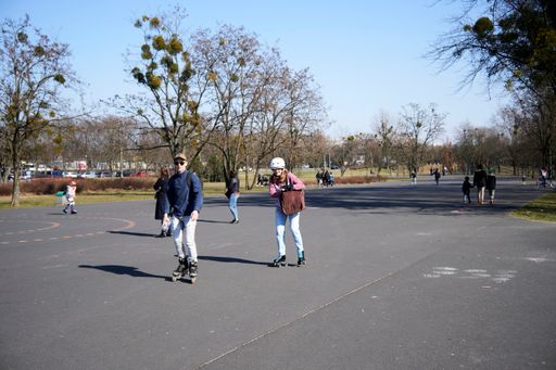 A young couple on roller skates on an asphalt area in the Jan Pawla park in Poznan, Poland