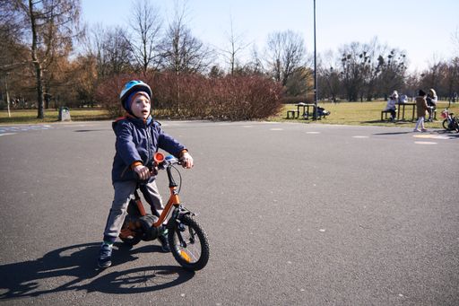 A young boy with a helmet sitting on a small bicycle in Jan Pawla park in Poznan, Poland