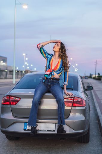 A vertical shot of beautiful girl sitting in the back of the car