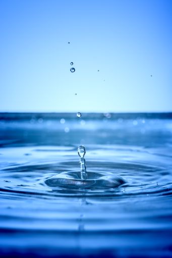 A vertical closeup of a beautiful waterdrop on a bluish background