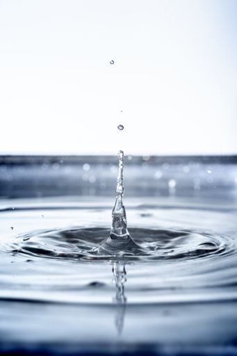 A vertical closeup of a beautiful waterdrop on a white background