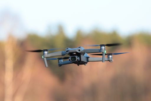 A closeup shot of a gray drone flying with blurred background