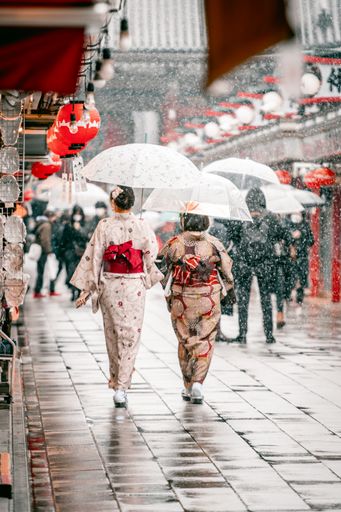A vertical shot of people walking in Japanese kimono during a rainy day