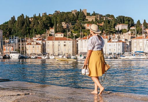 A rear view of Caucasian female walking in marina with sailing boats moored in Piran, Slovenia