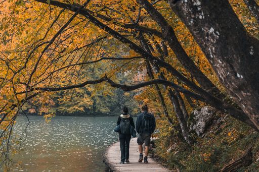 Two hikers walking on a path by an idyllic lake in autumn at Plitvice lakes national park in Croatia