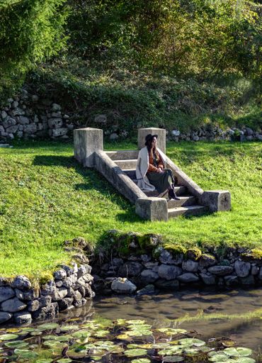 A Caucasian female sitting on the stairs in a park on a sunny day