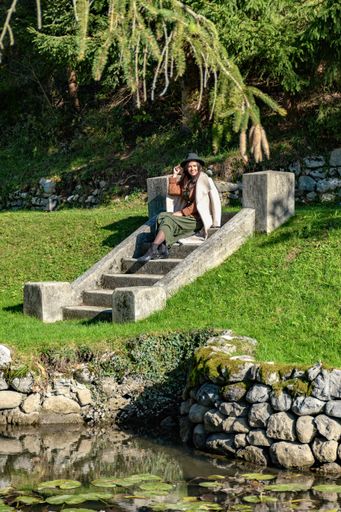 A Caucasian female sitting on the stairs in a park on a sunny day