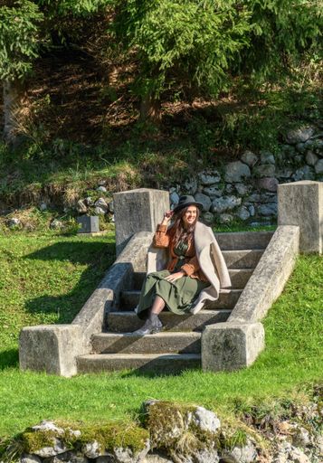A Caucasian female sitting on the stairs in a park on a sunny day