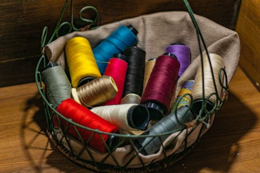 A closeup shot of colorful yarn rolls in a woven basket