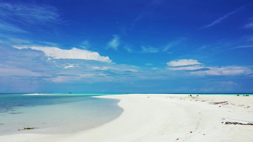 An aerial beautiful view of seascape with sandy beach under blue bright sky in Maldives
