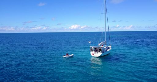 An aerial view of boat floating on sea under blue bright sky