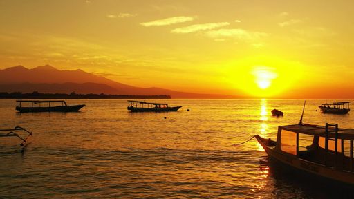 An aerial view of floating boats on sea in Maldives during sunset
