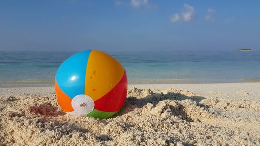 A beautiful shot of a colorful beach ball on the sand on a sea background