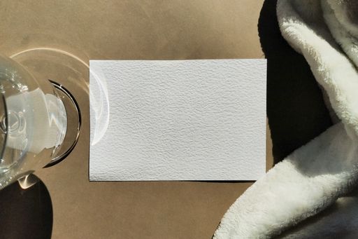 A top view closeup of a napkin on a table next to a glass and a white fabric