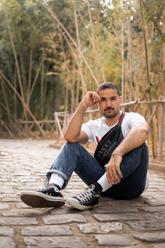 A caucasian model wearing a Gucci bag and a white Nasa t-shirt posing in a public park