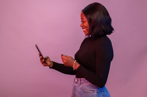 A closeup of the black woman using her phone and credit card.