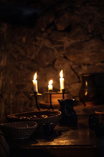 A vertical shot of a dark dining table with antique candles
