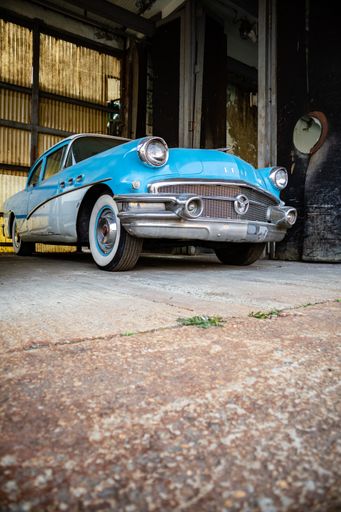 A vertical low angle closeup of a blue retro car in a garage