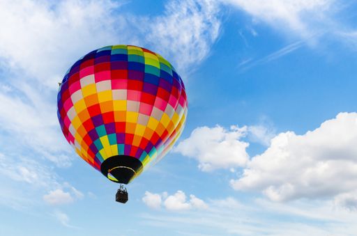 A colorful hot air balloon flying against the cloudy sky