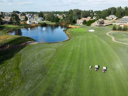An aerial view of golf course with golf carts by the lake