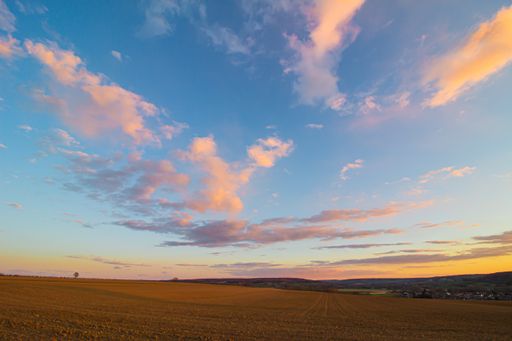 A bare agricultural field against a sunset sky