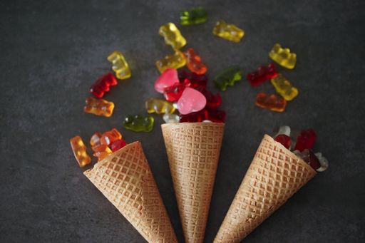 A top view of three waffle cones with colorful jellies on top on a gray surface