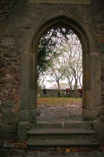 A vertical shot of the empty chairs in the garden, view from the stone arch.