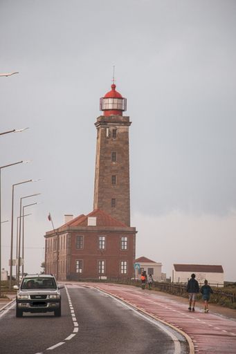 A vertical shot of a car on the road near a lighthouse in Nazare, Portugal