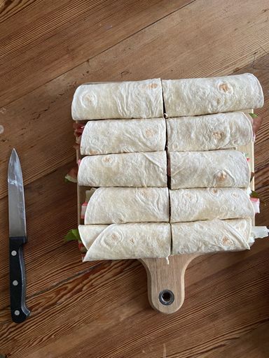 A top view of lavash wraps on a wooden table next by a knife