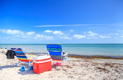 The chairs on the sandy beach on the coast under the cloudy blue sky