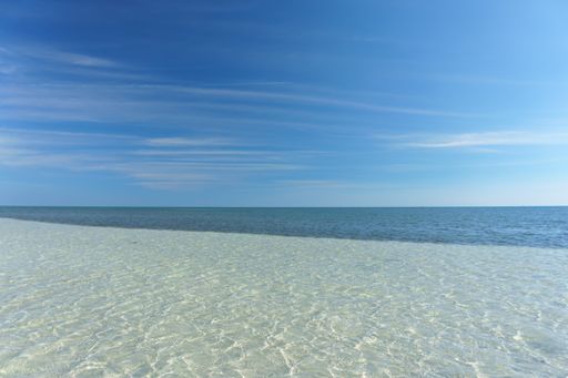 A beautiful view of the calm ocean gleaming under the cloudy blue sky on the coast