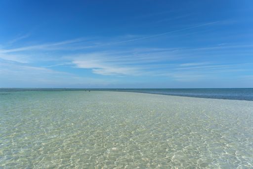 A beautiful view of the calm ocean gleaming under the cloudy blue sky on the coast