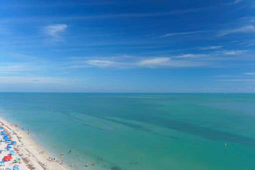 An aerial view of the beautiful sandy beach on the coast gleaming under the cloudy blue sky