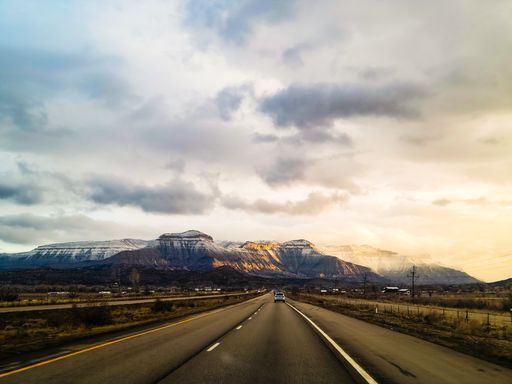 A highway leading to high mountains on the cloudy sunset in Debeque, USA